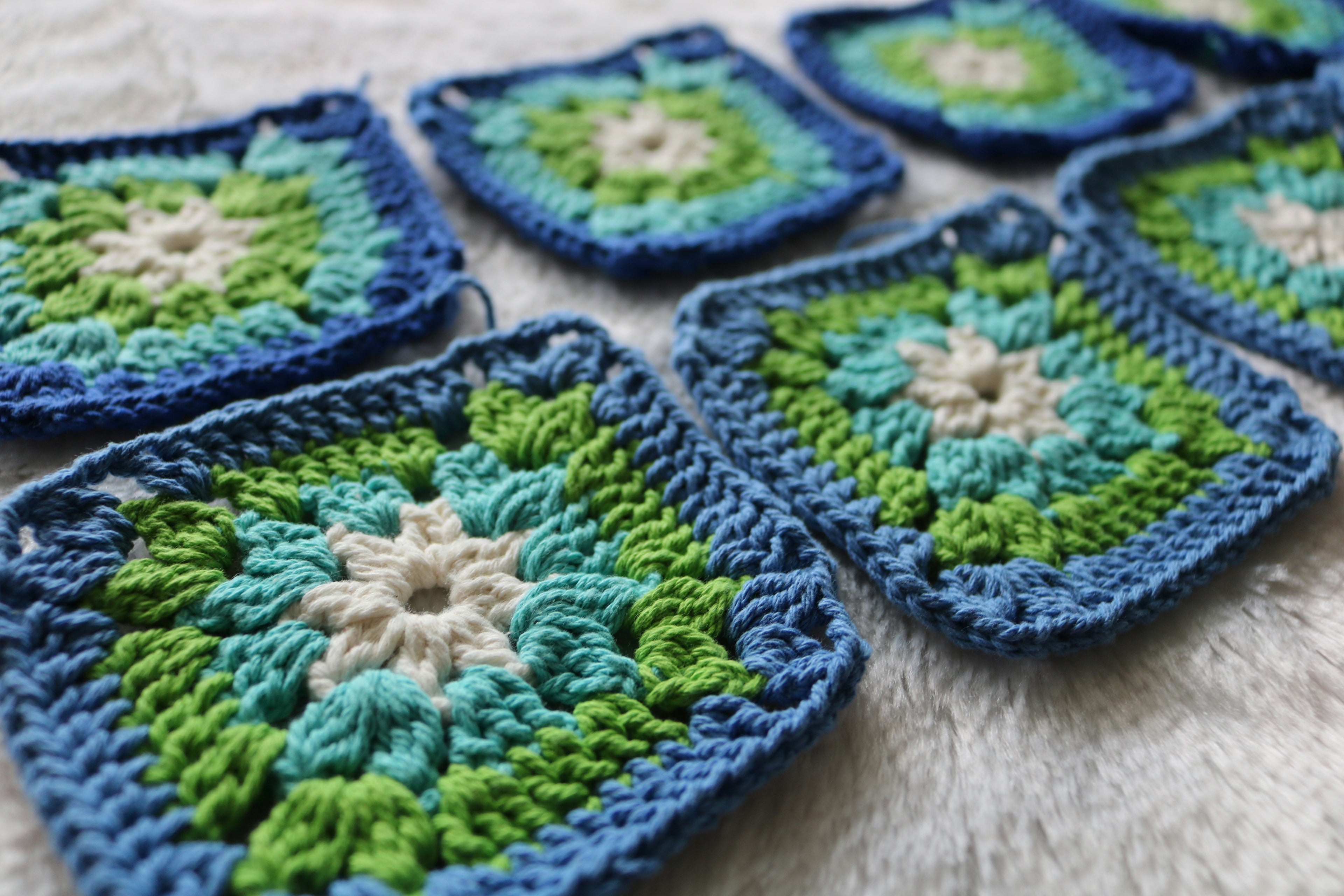 Bohemian cotton crochet granny squares in blue, green, teal and white, arranged to show handcrafted texture and vibrant colour blend